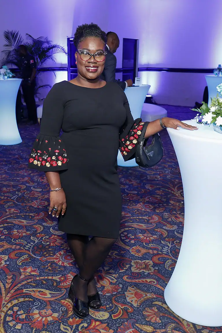 Elegant woman at a corporate event with high-tech lighting, representing financial growth and investment strategies, wearing a stylish black dress with embroidered sleeves for modern professionalism.