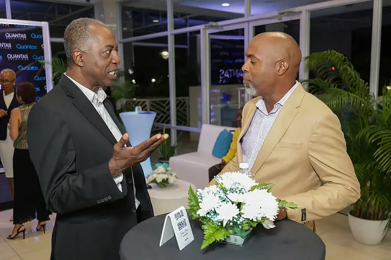 Business professionals engaging in conversation at a corporate event, emphasizing networking and partnership opportunities in the financial or investment industry.